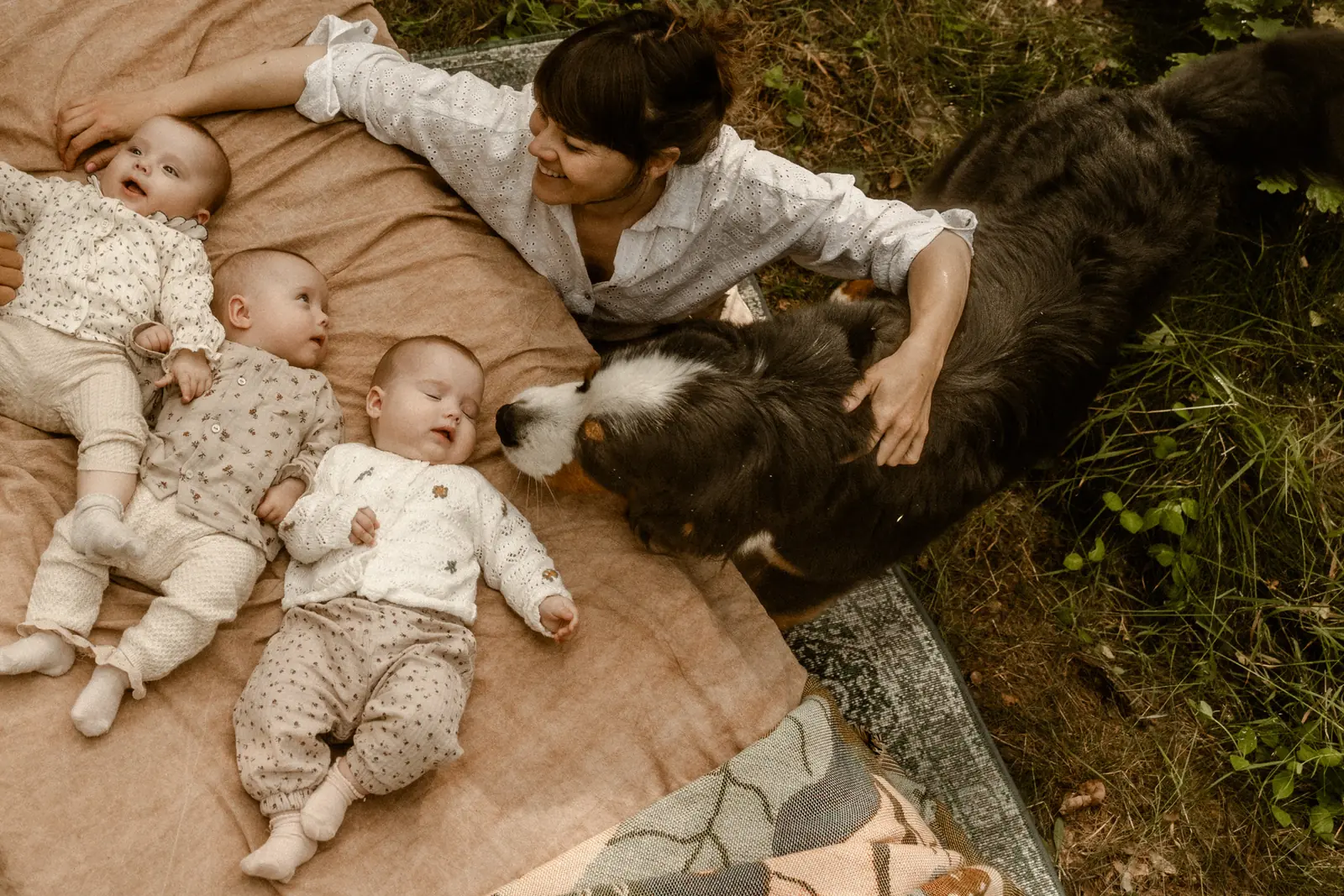 Mama z trójką rodzeństwa niemowlaków w towarzystwie psa podczas naturalnej sesji w stylu filmowym