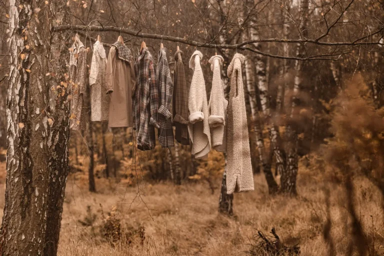 Garderoba na sesją zdjęciową powieszona na wieszakach zwisają na gałęzi drzewa w środku lasu