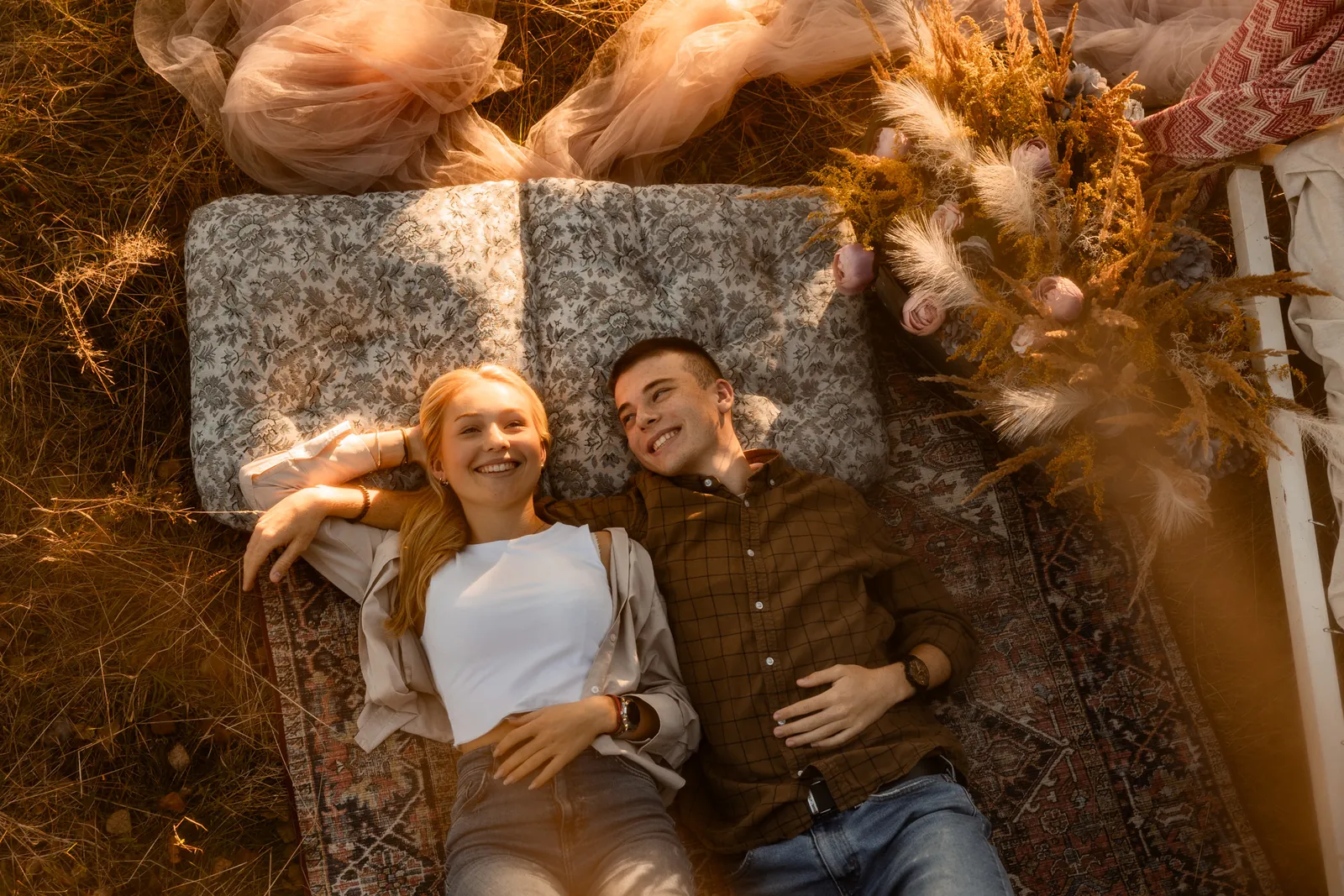 Zakochana para leży na dywanie wśród drzew i miękkiego porannego światła