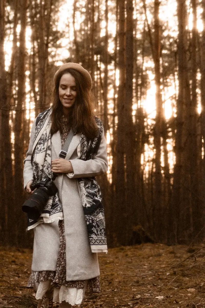 Fotograf idzie przez las z aparatem i robi sesje zdjęciową w plenerze