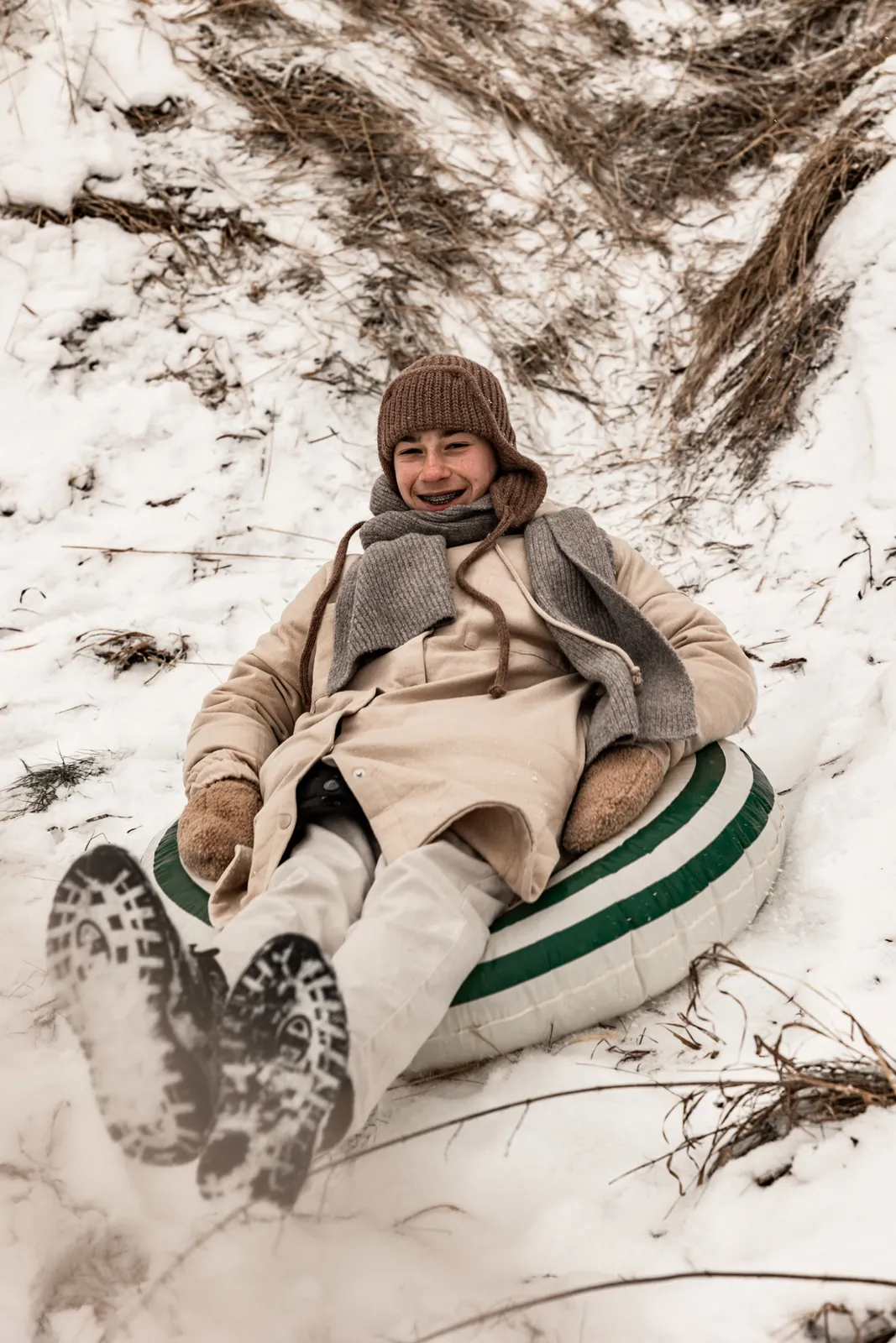 Chłopak zjeżdża z górki śniegu na kole dmuchanym podczas rodzinnej sesji zdjęciowej w plenerze