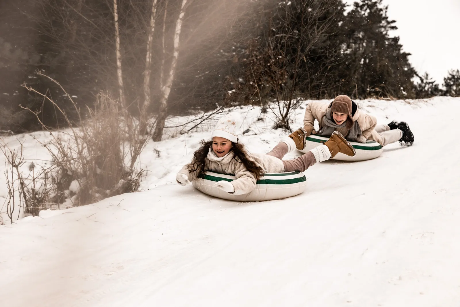 Brat próbuje dogonić siostrę podczas zjazdu z górki śniegu na dmuchanych kołach