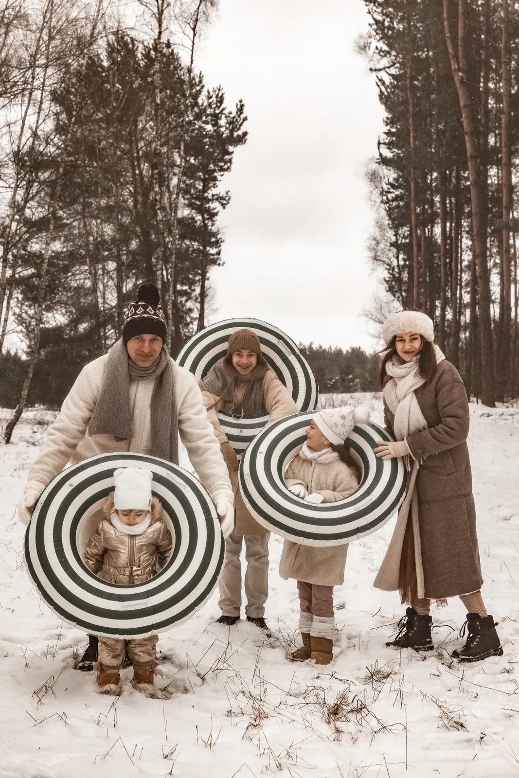 Rodzinny portret w naturalnej zimowej scenerii z dmuchanymi kołami na śnieg podczas sesji zdjęciowej