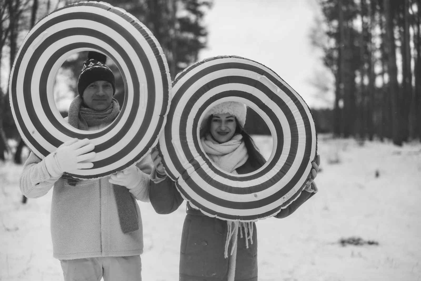 Rodzice wypatrują swoje dzieci przez dmuchane koła na śnieg podczas zimowej sesji zdjęciowej w plenerze