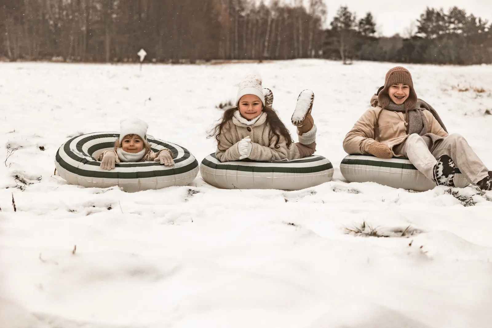 Dzieci siedzą na dmuchanych kołach na śnieg podczas zimowej sesji rodzinnej w plenerze