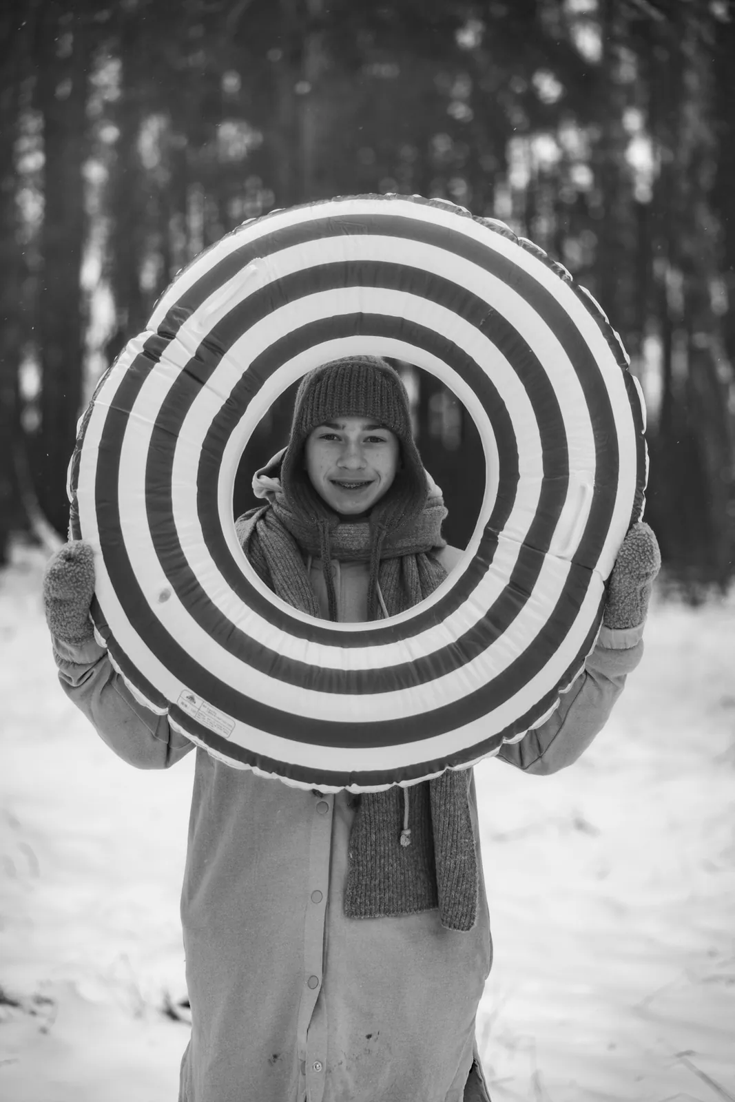 Czarno-biały portret chłopca z kołem podczas zimowej sesji zdjęciowej